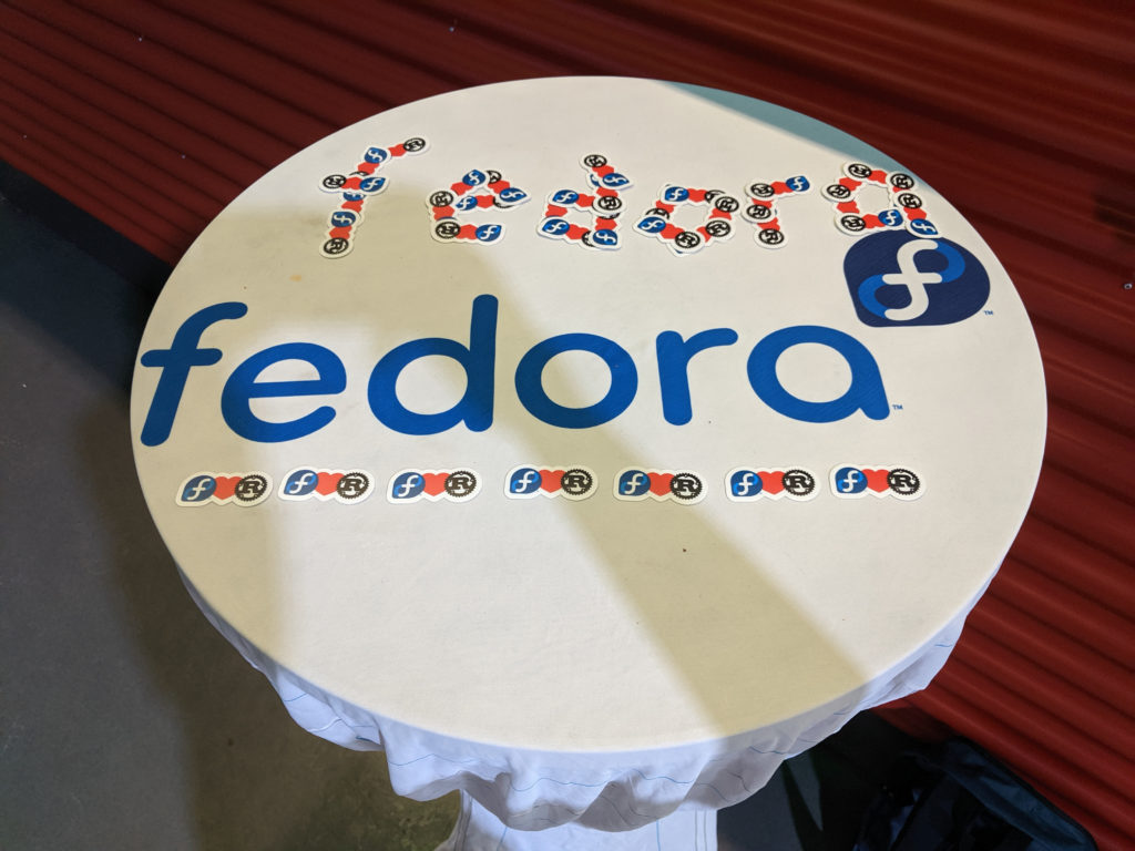 Table with fedora logo out of FedoraLovesRust stickers.