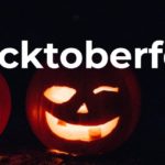 Lit jack-o-lanterns in a dark location with the white text "Hacktoberfest"