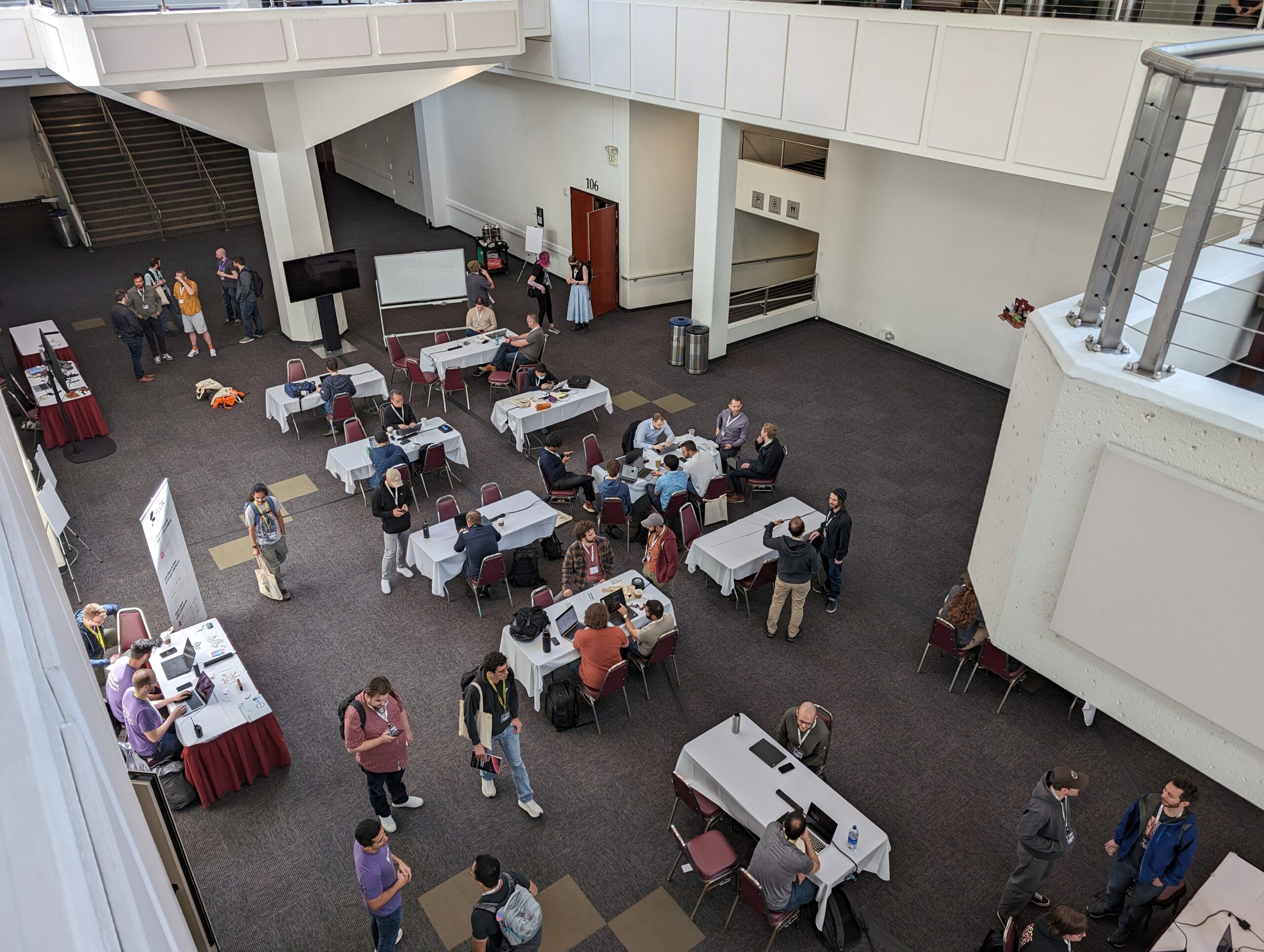 top-down view of the first floor of the Pasadena Conference Center from the second floor balcony. a picture of 40+ people chatting and/or working on laptops
