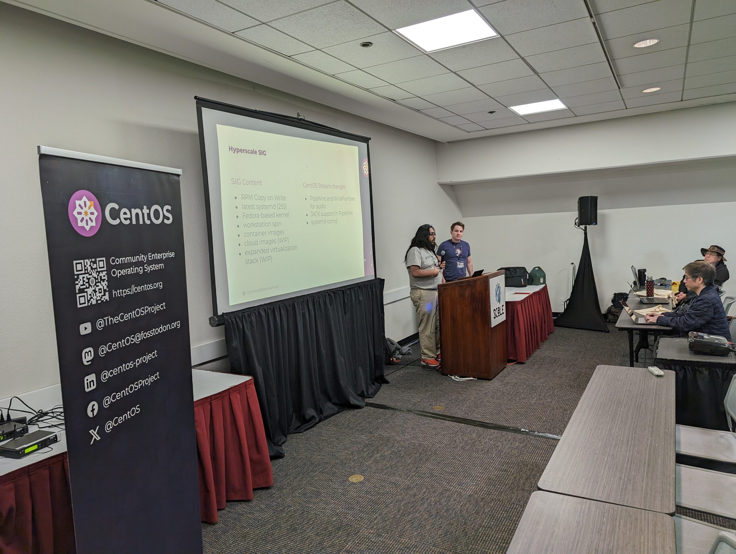 Photo of Neil Gompa, Shaun McCance at the podium presenting a kernels talk. Photo taken by Carl George.